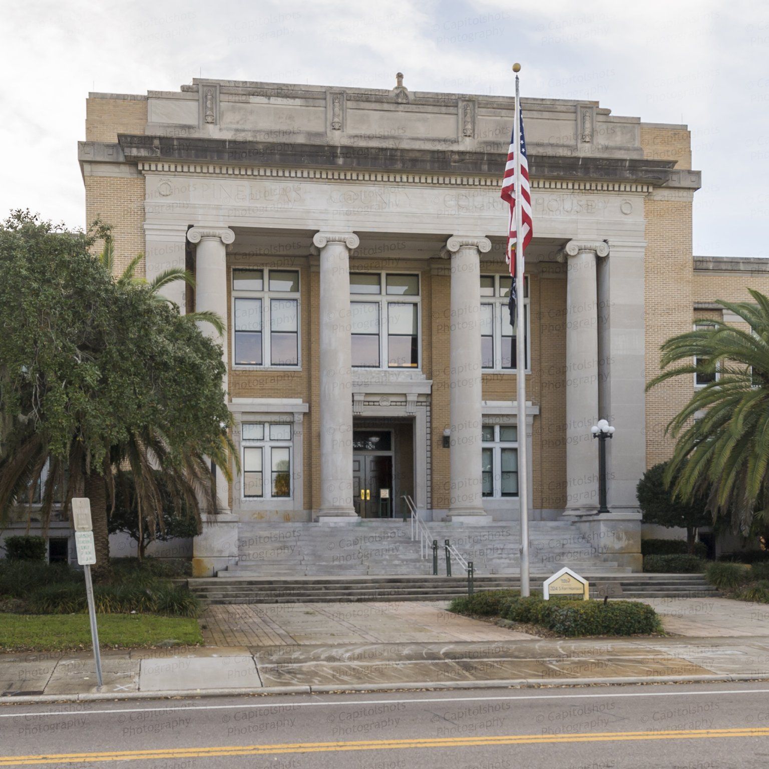 Historic courthouse with columns, American flag, and palm trees.