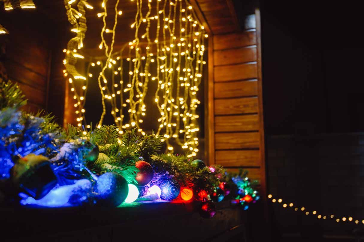 Holiday lights glowing on a porch with blue, red, and green decorations at night