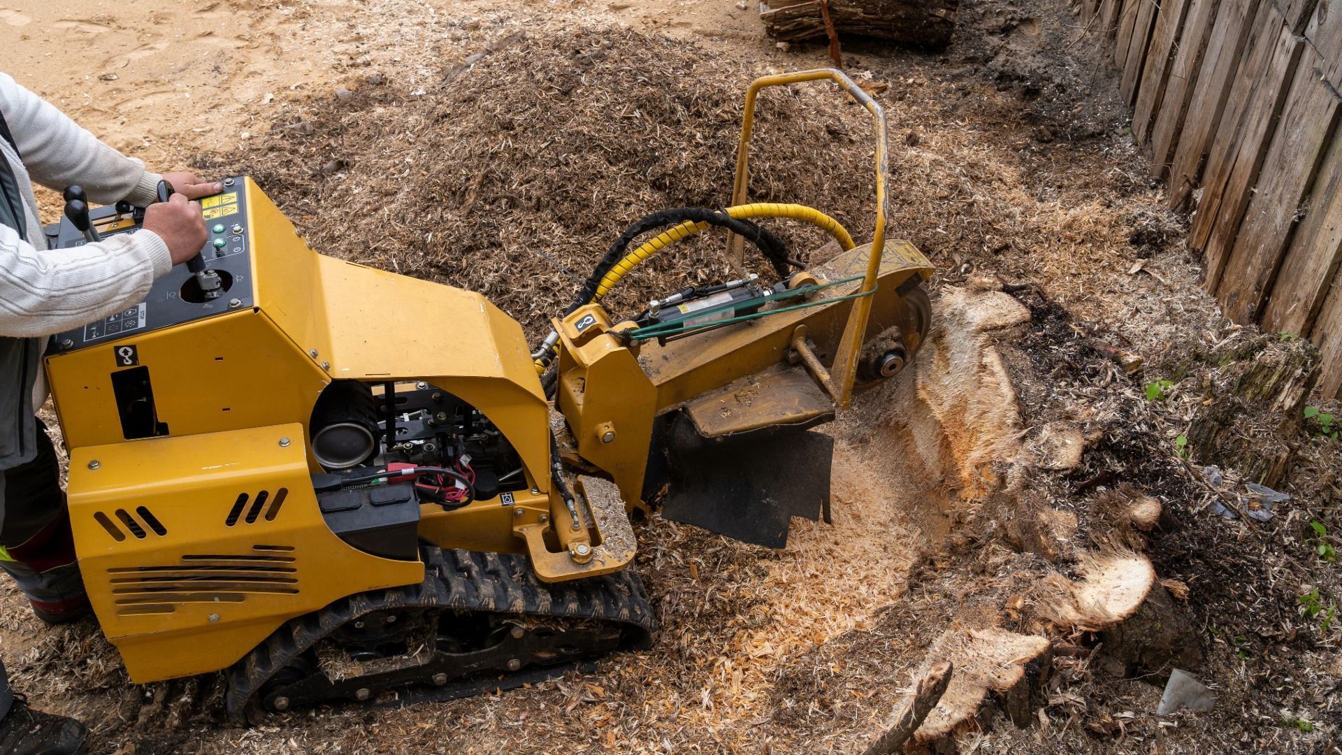Yellow mini excavator clearing dirt on a rocky slope
