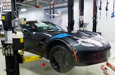 Une corvette noire est assise sur un ascenseur dans un garage.