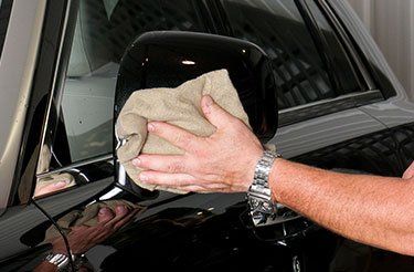 Un homme nettoie une voiture avec une serviette
