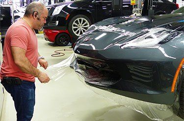 Un homme enveloppe une voiture avec du film plastique dans un garage.