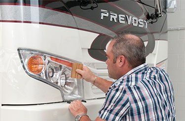 Un homme nettoie les phares d'un camping-car.