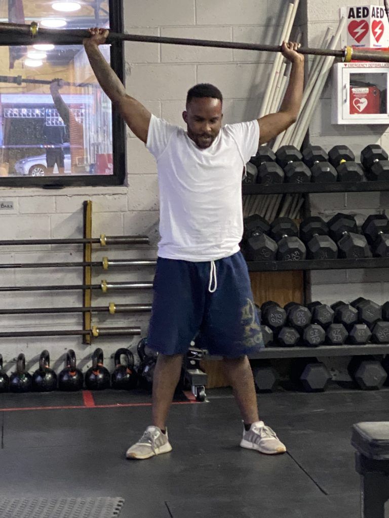 A man is holding a barbell over his head in a gym.
