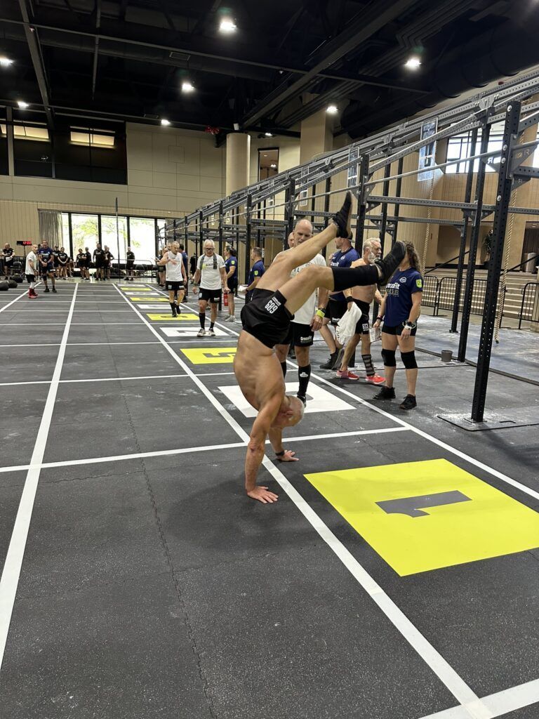 A man is doing a handstand on a gym floor.