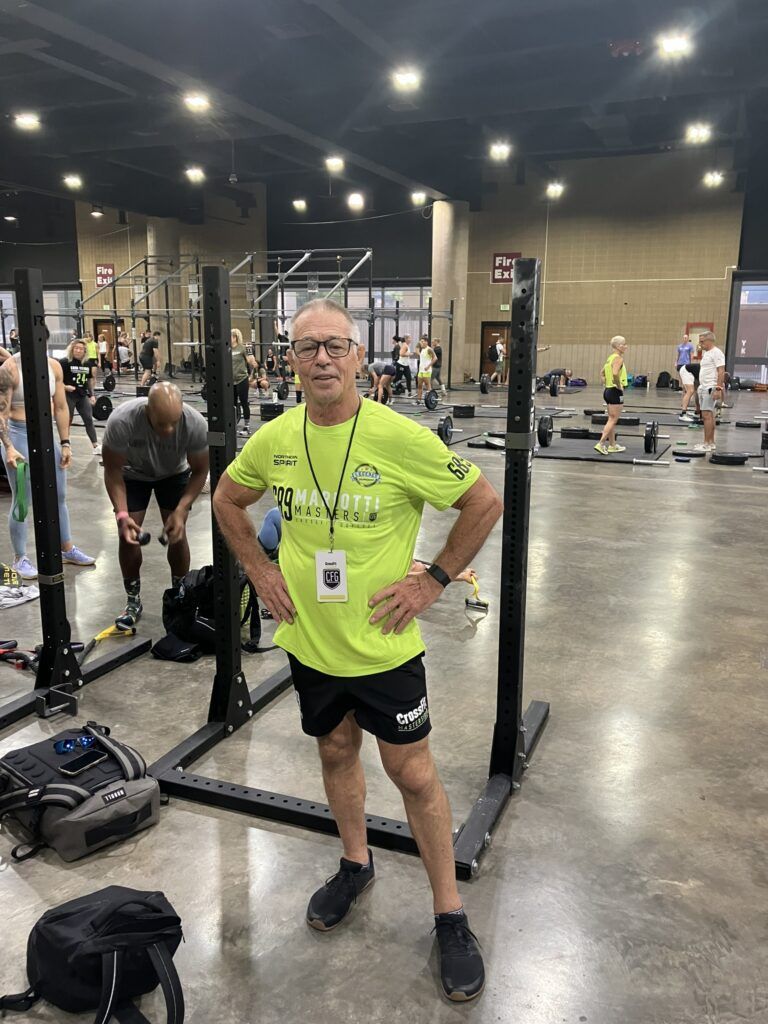 A man is standing in a gym with his hands on his hips.
