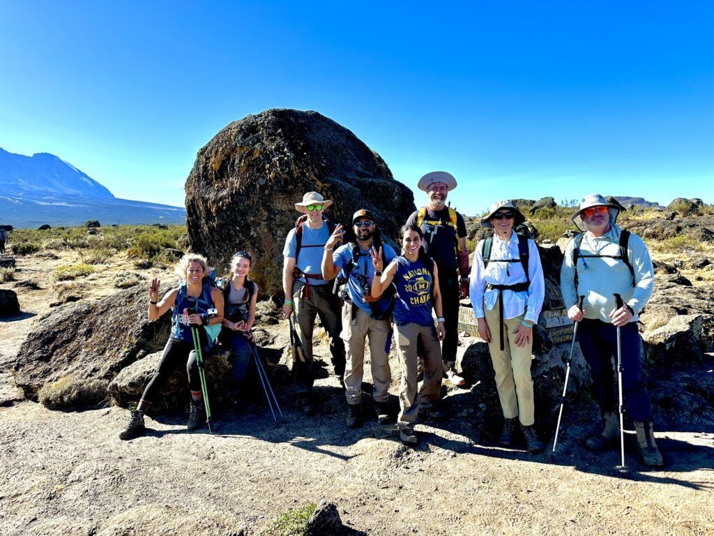A group of people are posing for a picture in front of a large rock.