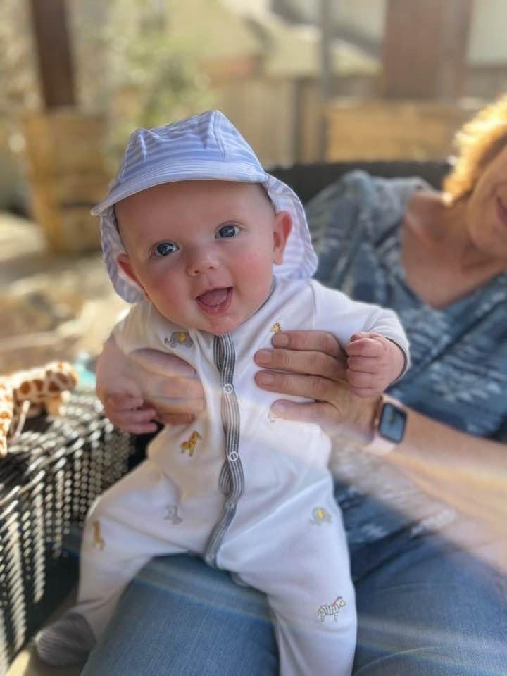 A woman is holding a baby wearing a hat.