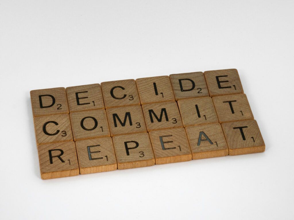 Scrabble tiles with the words decide commit repeat written on them