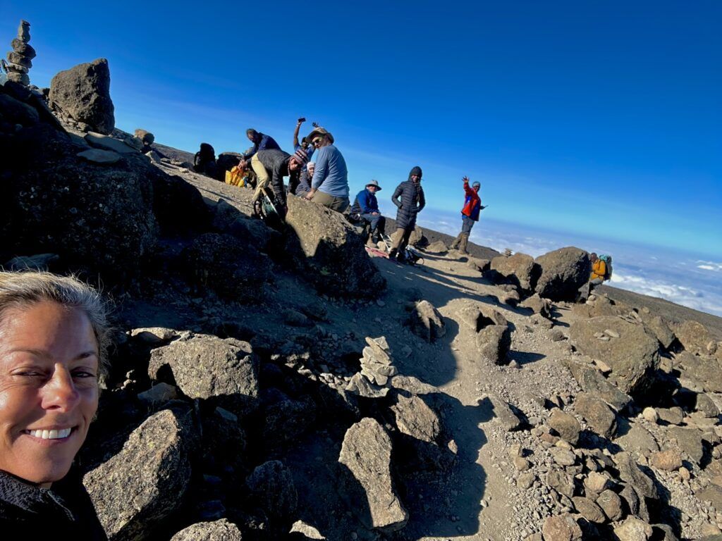 A woman is taking a selfie on top of a rocky mountain.