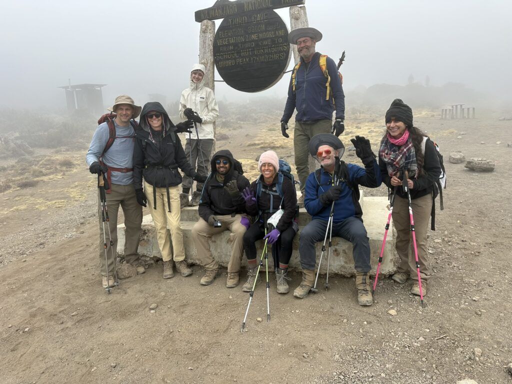 A group of people are posing for a picture on top of a mountain.
