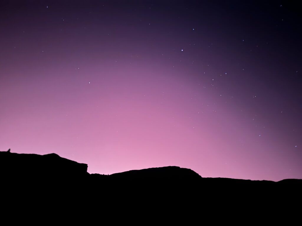 A purple sky with stars and mountains in the foreground
