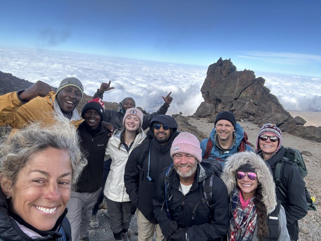 A group of people are posing for a picture on top of a mountain.