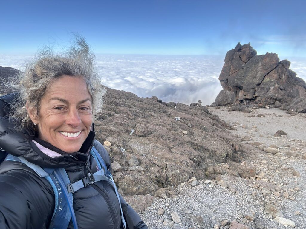 A woman is taking a selfie on top of a mountain.