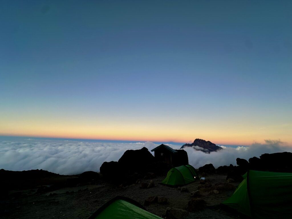 A group of green tents are sitting on top of a mountain