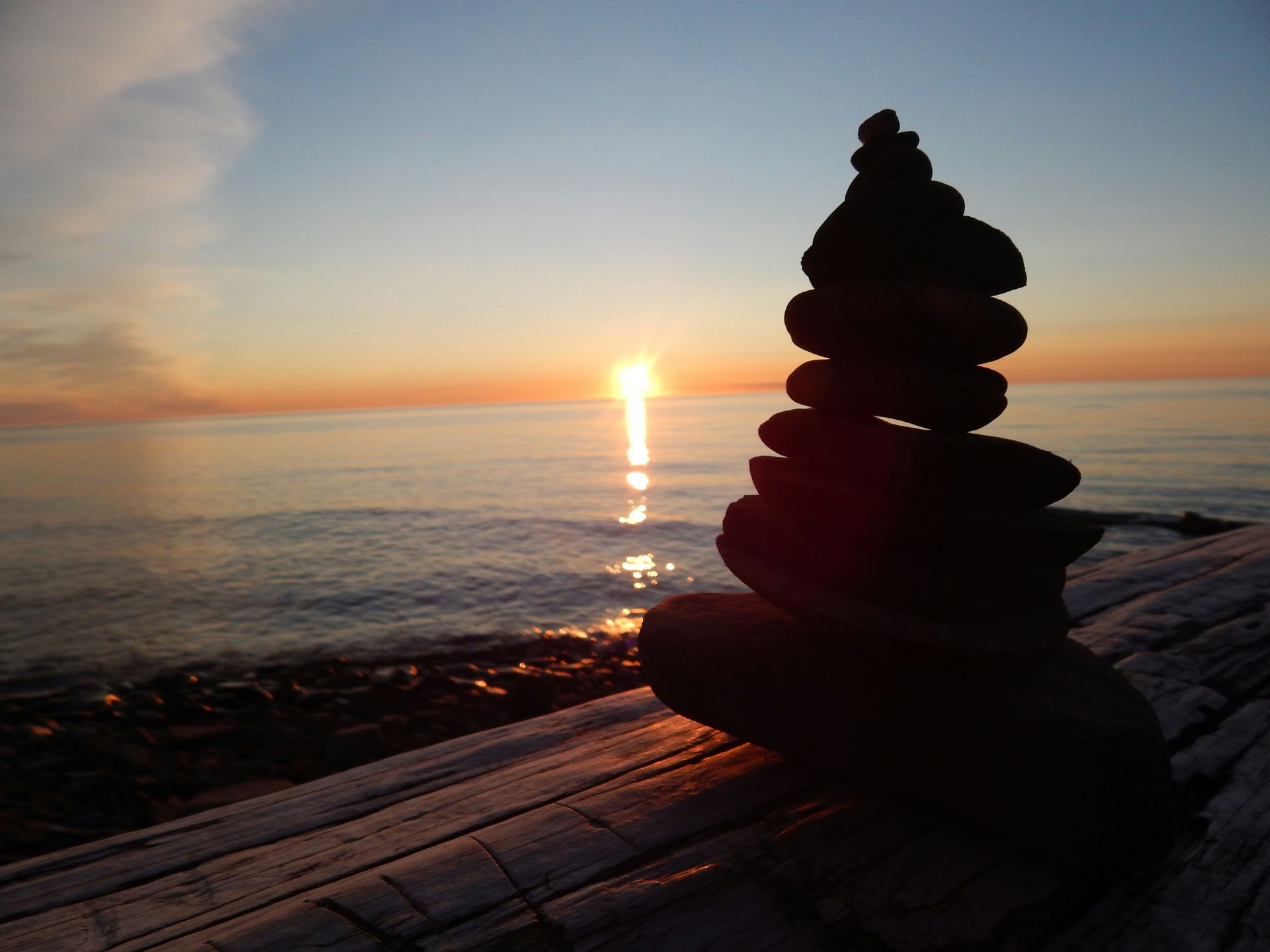 A stack of rocks on a beach with the sun setting in the background