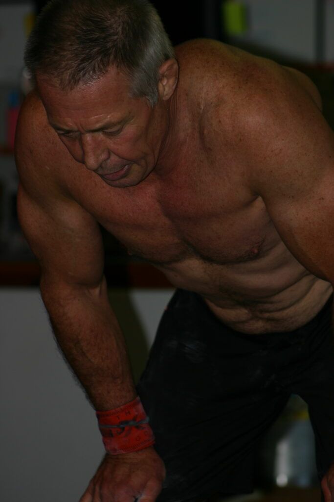 A shirtless man is doing push ups in a gym.