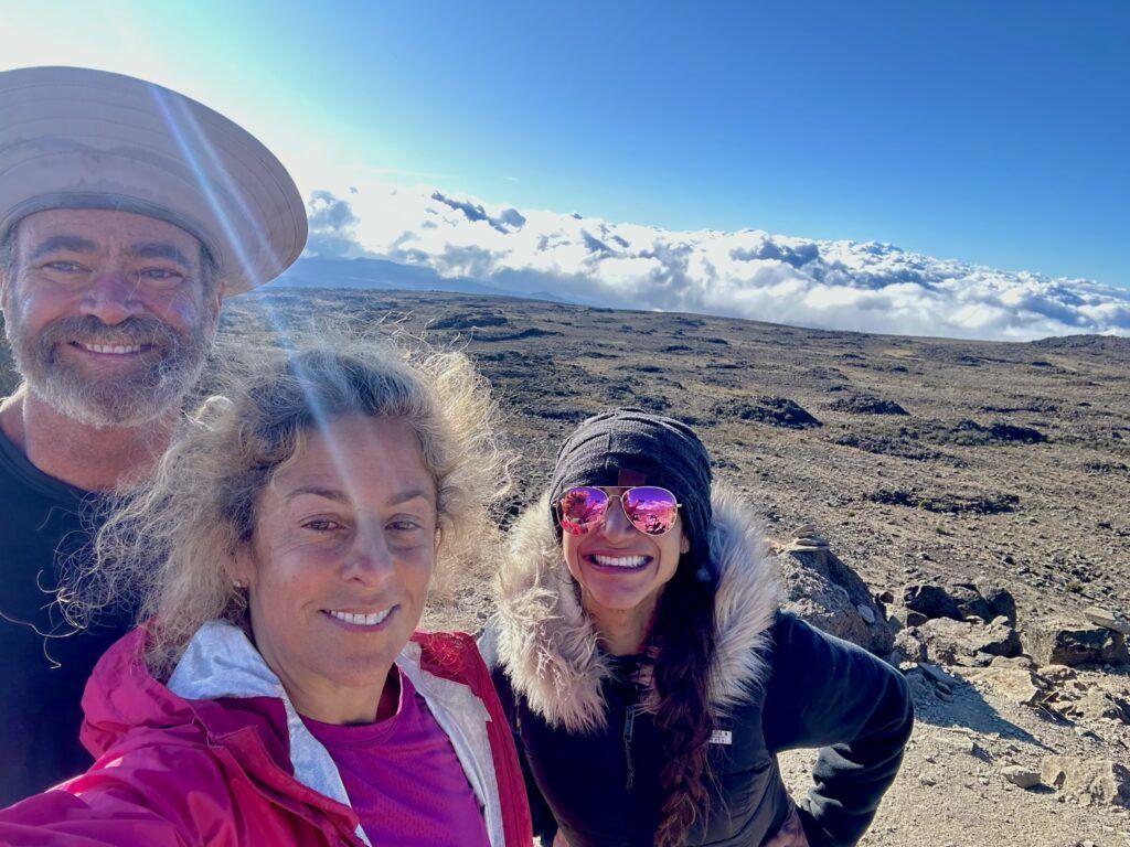 A man and two women are posing for a picture on top of a mountain.