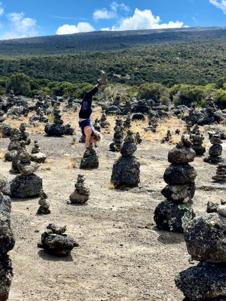 A person is doing a handstand in a field of rocks.