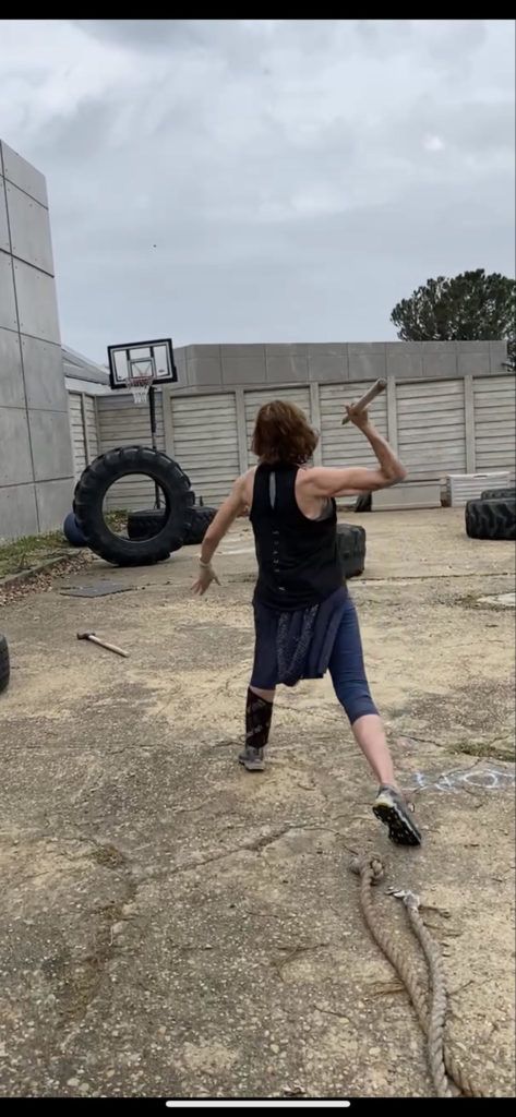 A man is throwing a hammer in a dirt field.