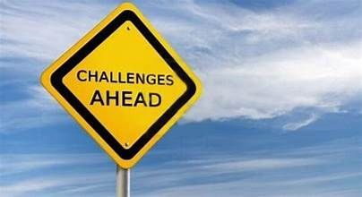 A yellow sign that says `` challenges ahead '' is against a blue sky.