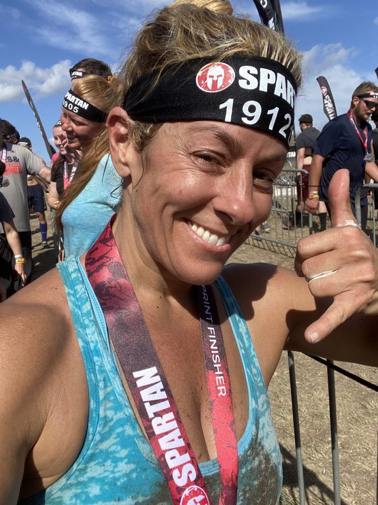 A woman is wearing a spartan headband and giving a thumbs up.