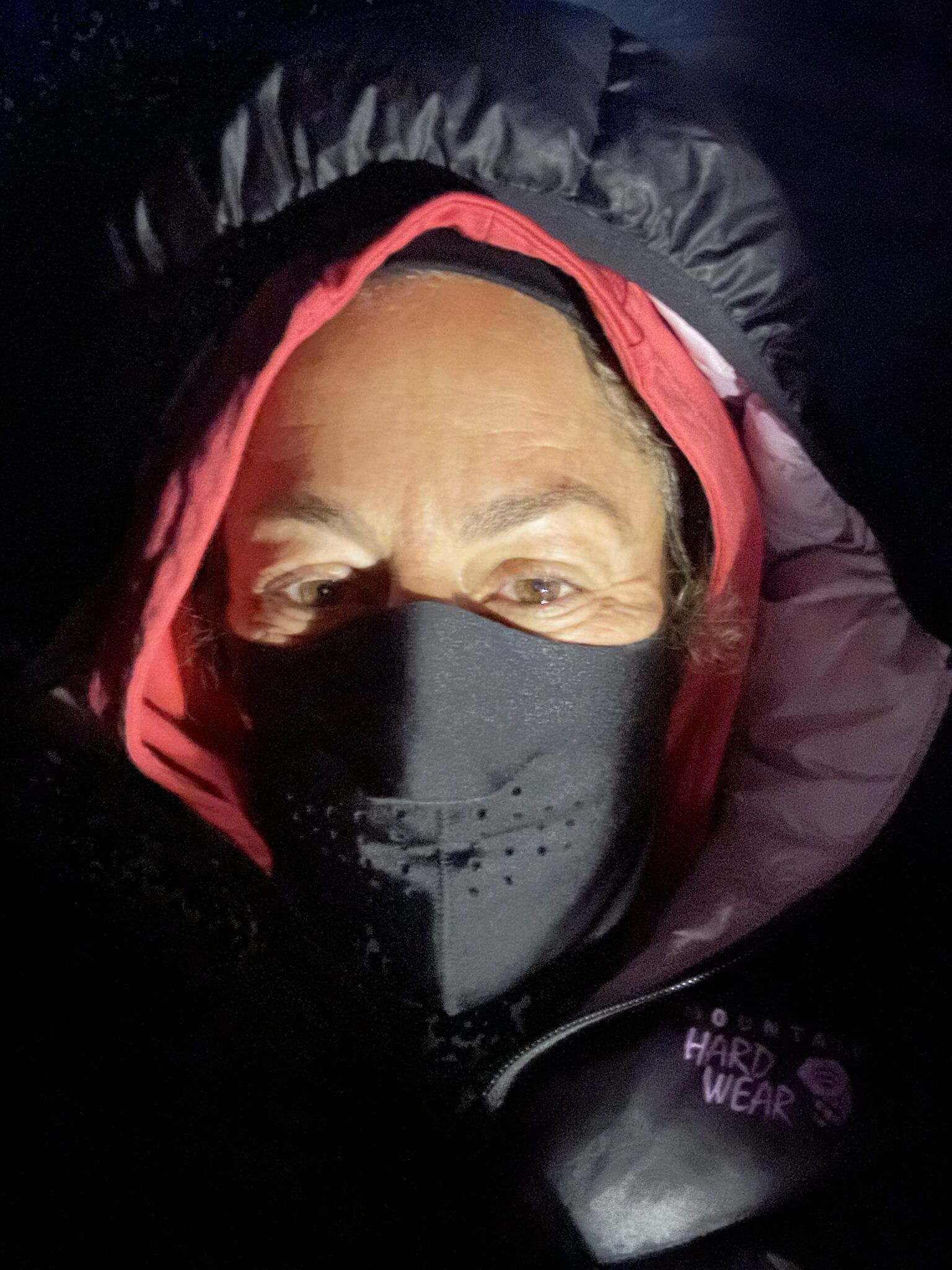 A man wearing a black mask and a red hood.