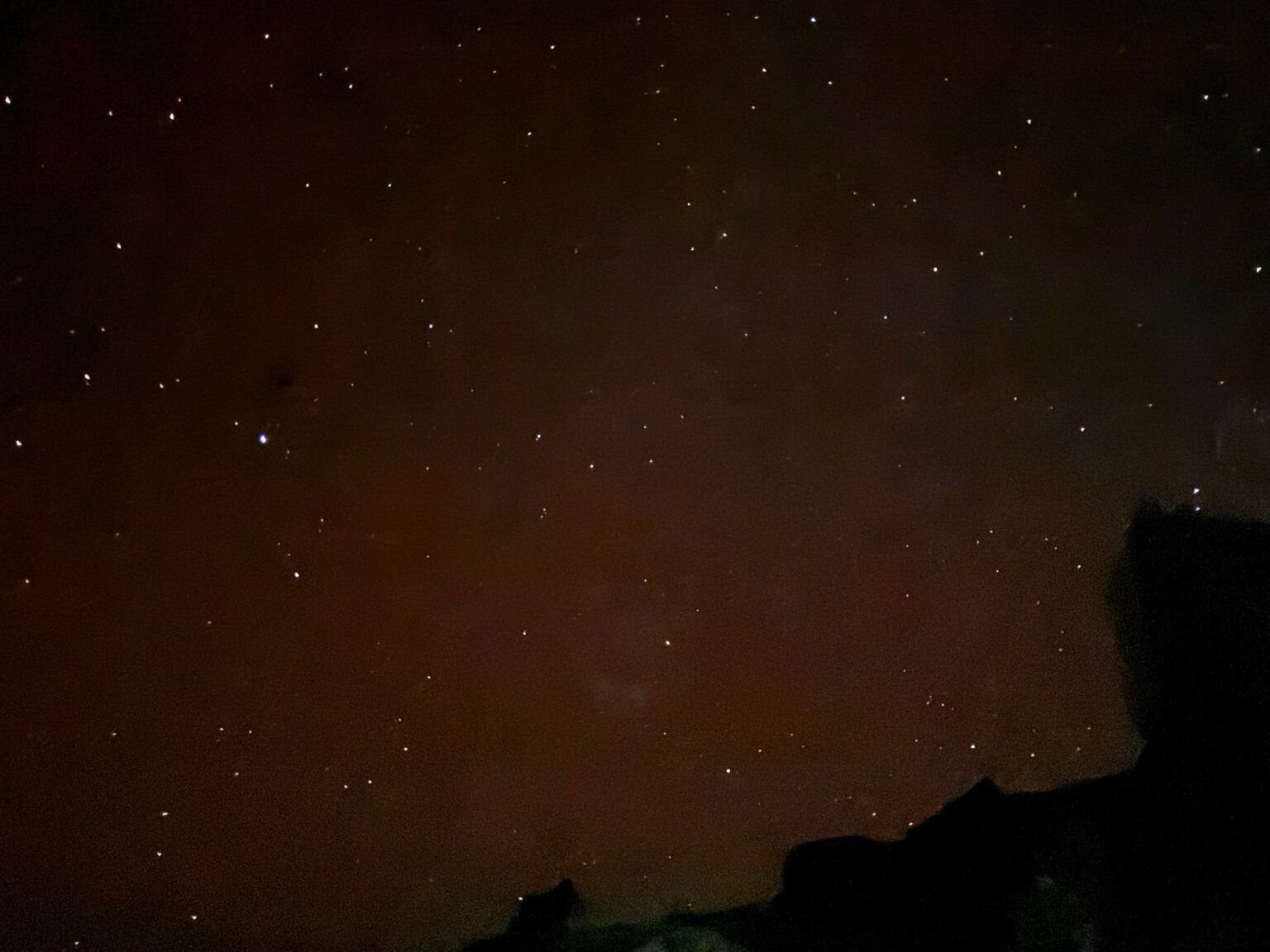 A night sky filled with lots of stars and a mountain in the foreground.