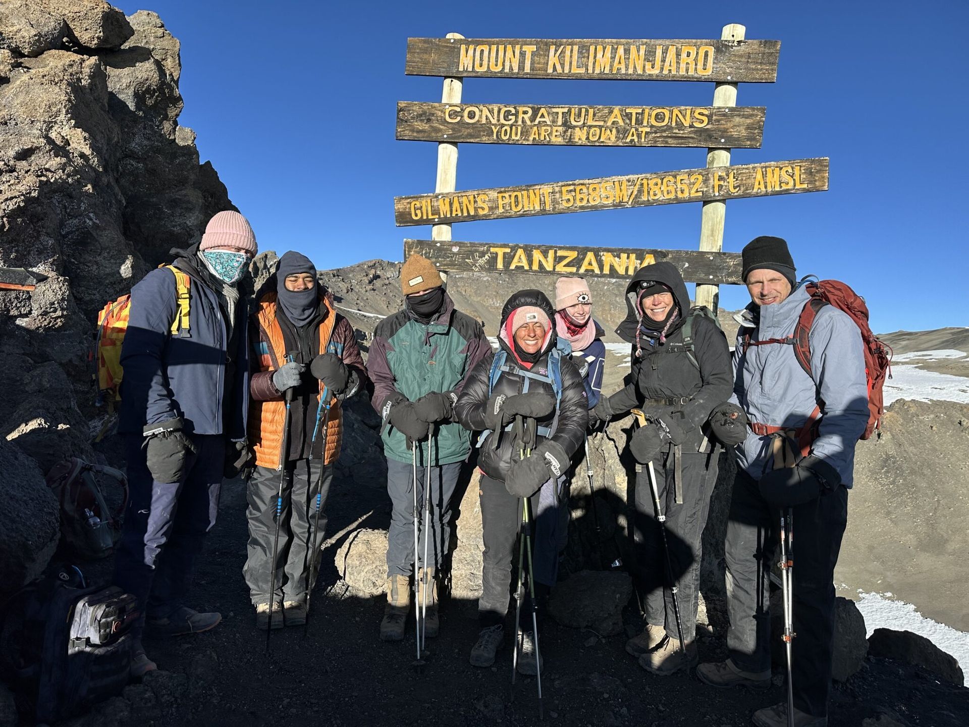 A group of people are standing in front of a sign that says mount kilimanjaro.