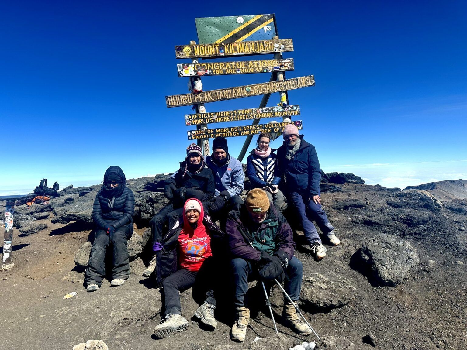 A group of people are posing for a picture on top of a mountain.