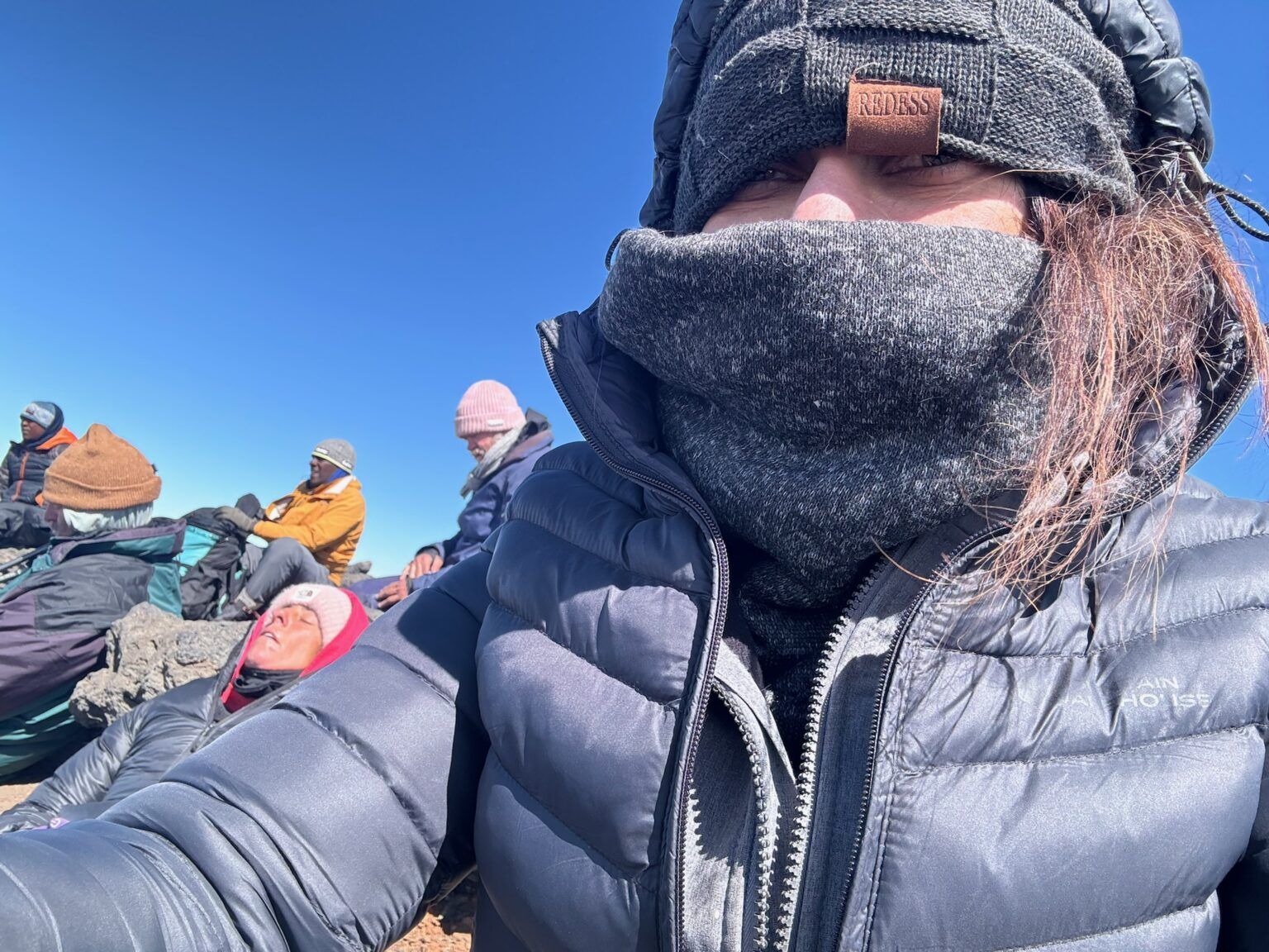 A woman wearing a scarf and a hat is taking a selfie.