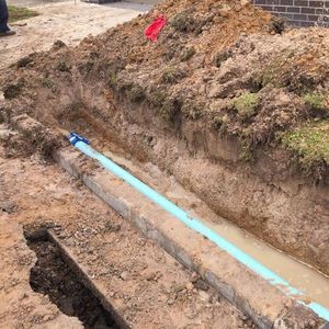 a blue pipe is laying in the dirt next to a brick wall .