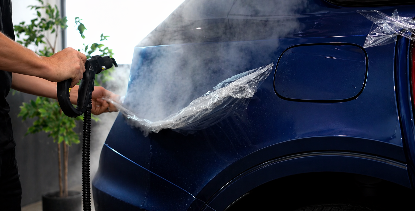Technician using steam to remove aged conventional paint protection film from the rear quarter panel