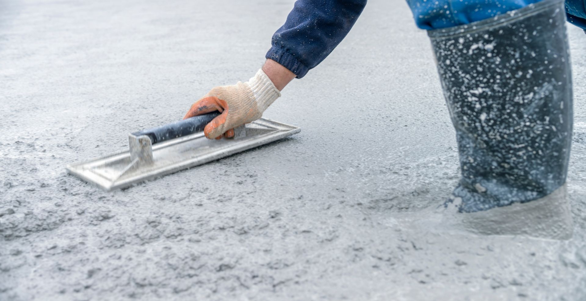 Residential concrete contractor smoothing concrete with a trowel in a home construction setting. Residential concrete contractor smoothing concrete with a trowel in a home construction setting.