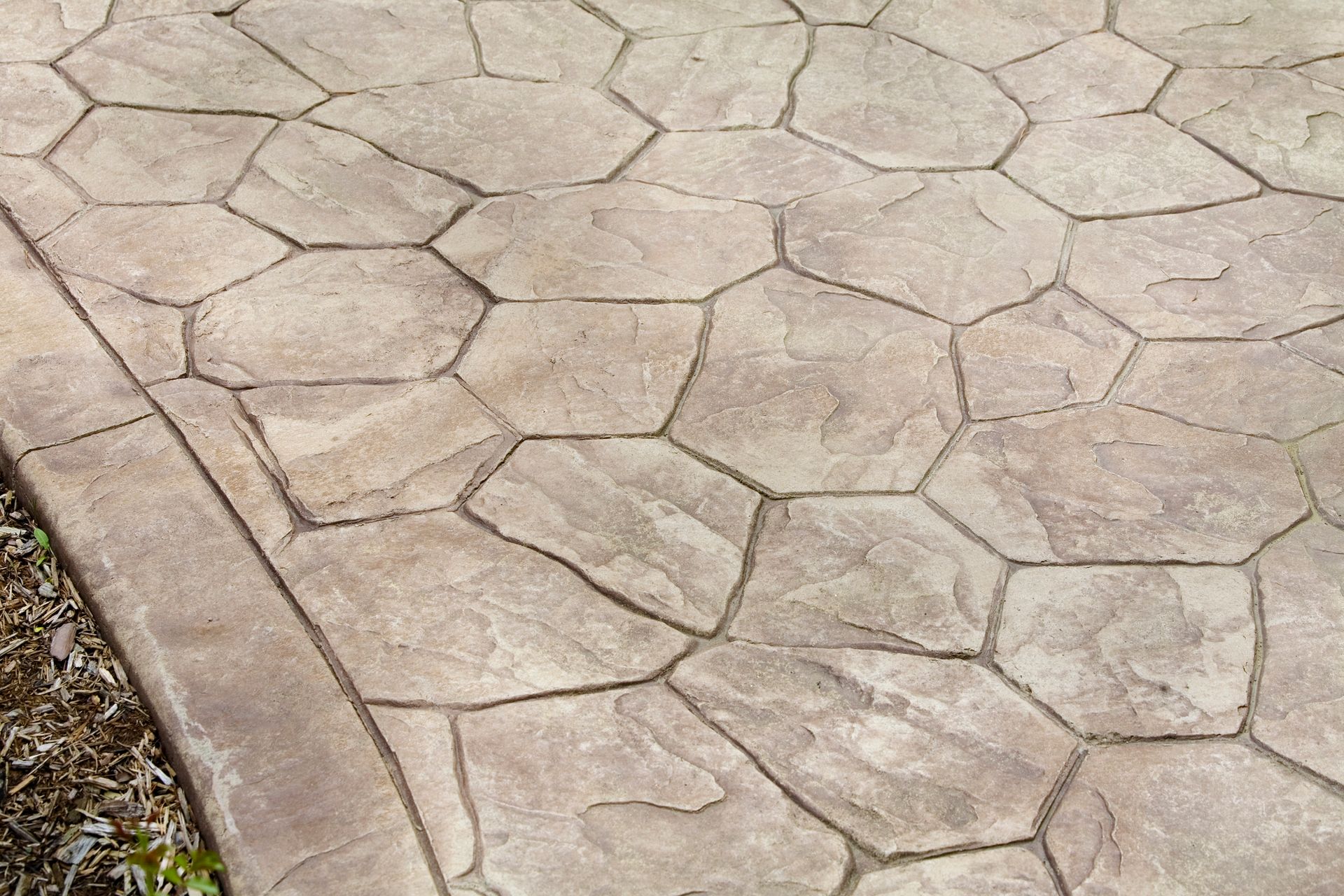 Textured concrete patio with a flagstone pattern in tan and brown.