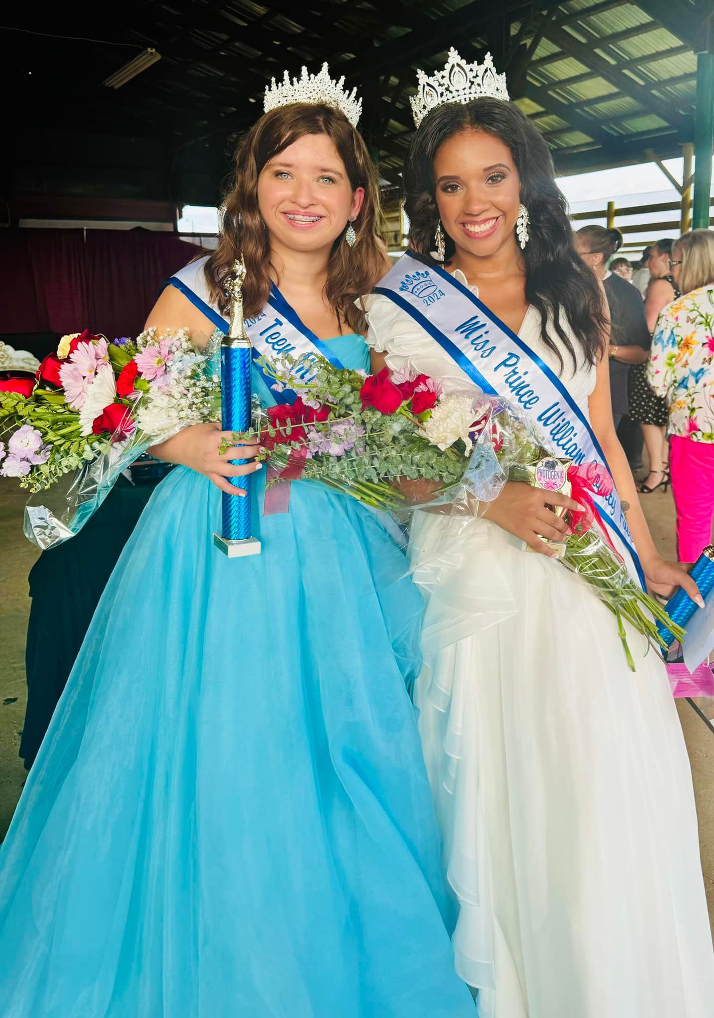 Two women in dresses are standing next to each other holding flowers.