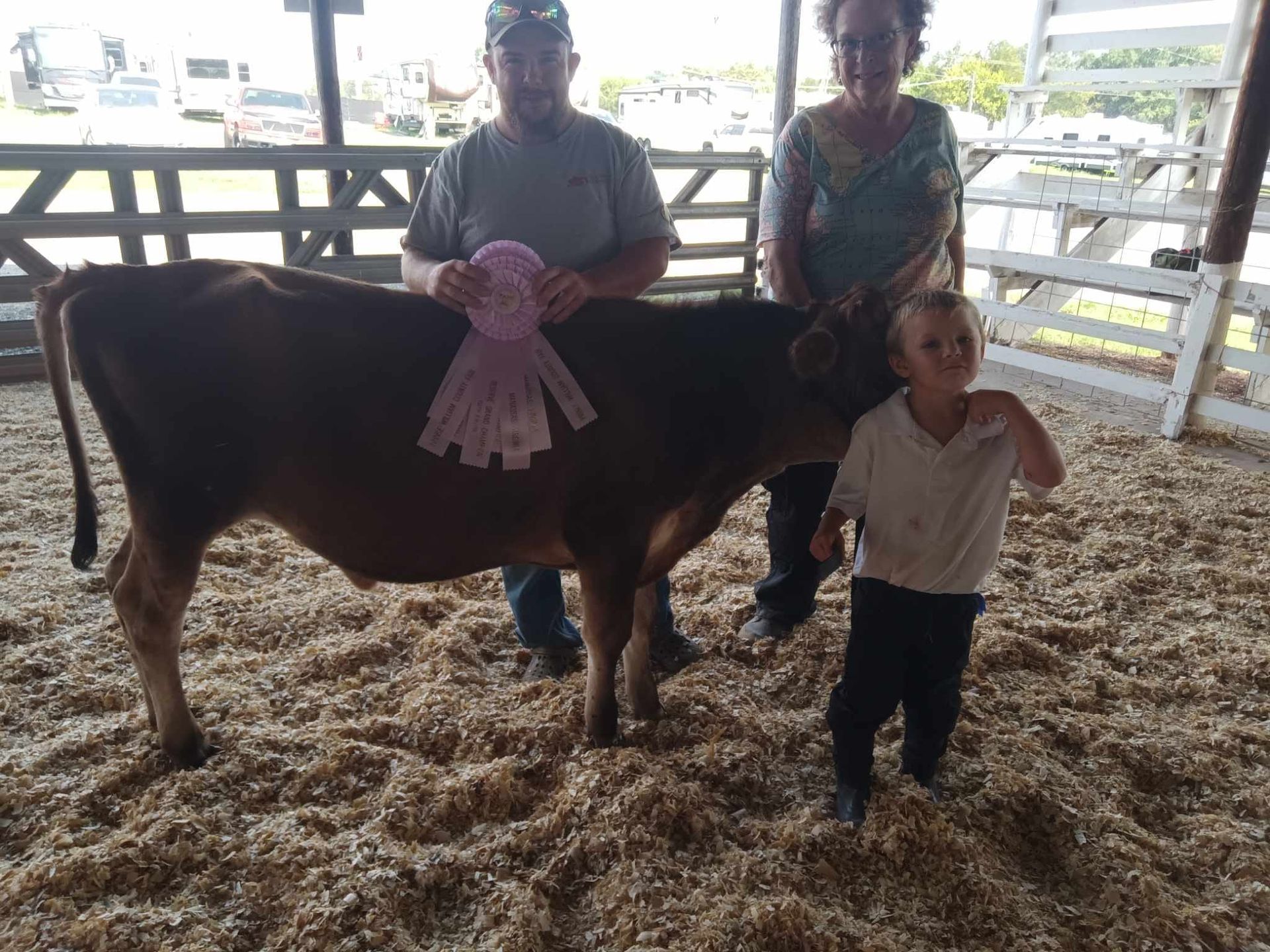 A couple of people standing next to a cow with a ribbon on it
