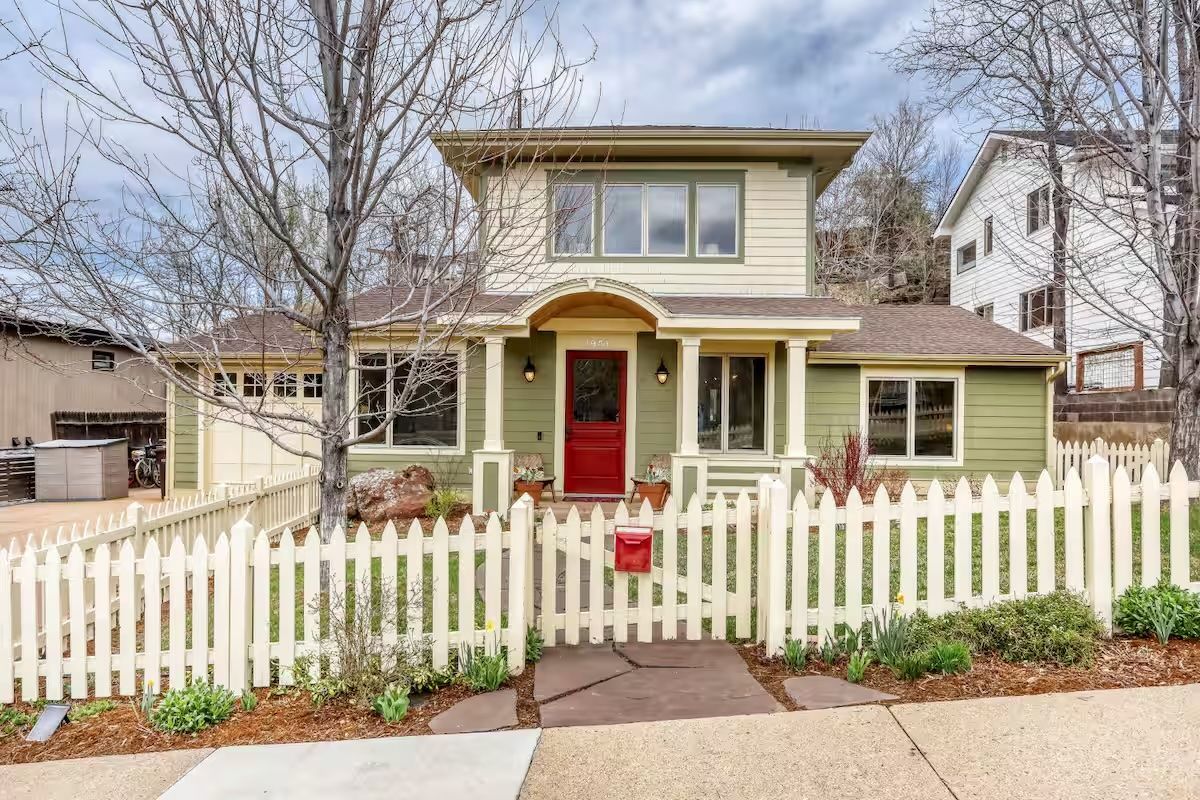 A nice, older home with green siding and a white picket fence.
