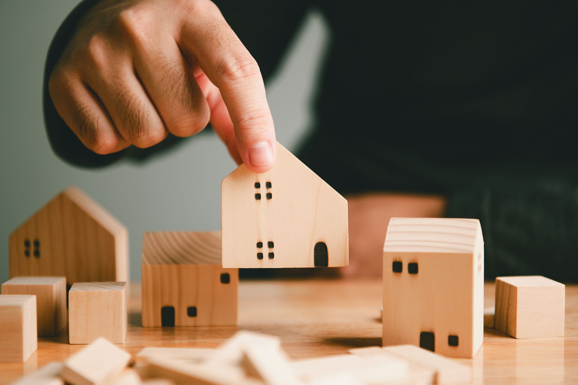 property management concept with hand arranging small wooden houses