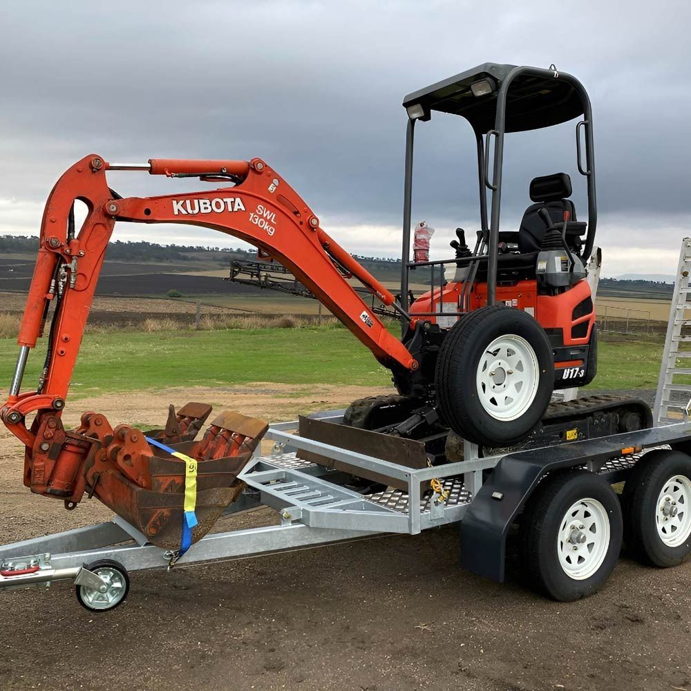 A Small Orange Kubota Excavator Is Loaded On A Trailer — NQES Industries in Julia Creek, QLD