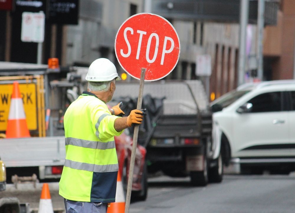 A Man Is Holding A Stop Sign On The Street — NQES Industries in Ryan, QLD
