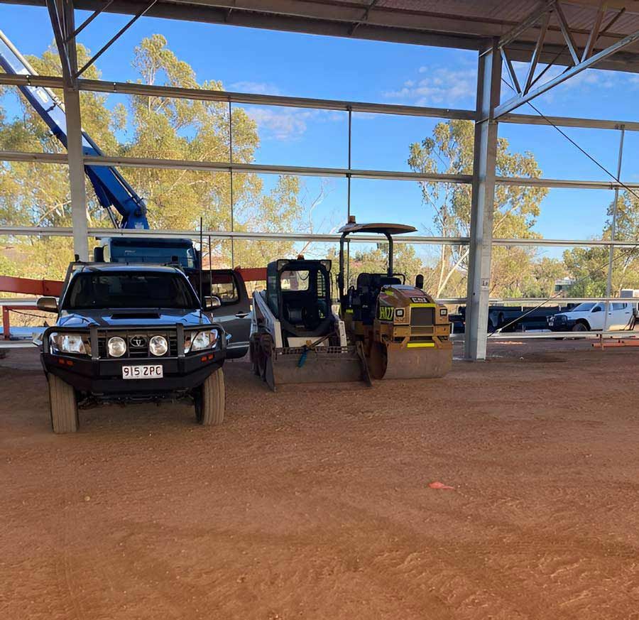 A Truck Is Parked Next To A Bulldozer On The Big Metal Shed — NQES Industries in Ryan, QLD