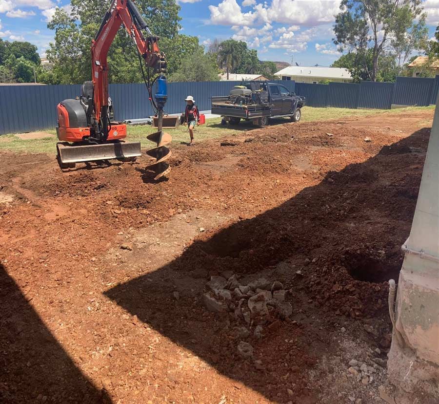 An Excavator Is Digging A Hole In The Ground In A Dirt Field — NQES Industries in Ryan, QLD