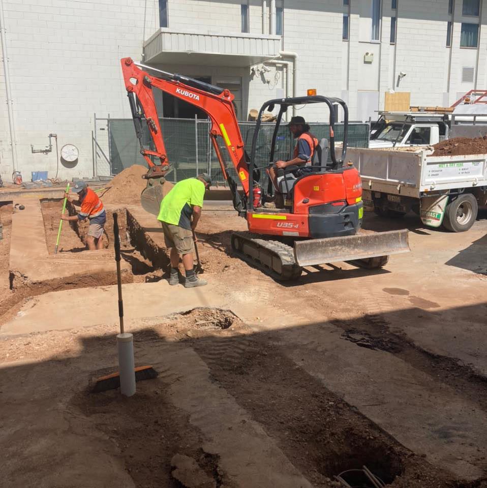 A Man In A Yellow Shirt Is Standing Next To A Red Excavator — NQES Industries in Ryan, QLD