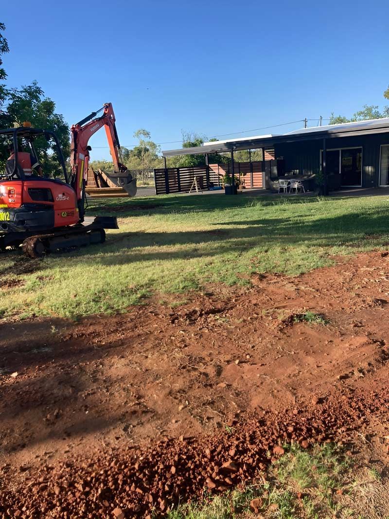 An Excavator Is Parked In A Dirt Field In Front Of A House After Digging A Trench — NQES Industries in Ryan, QLD