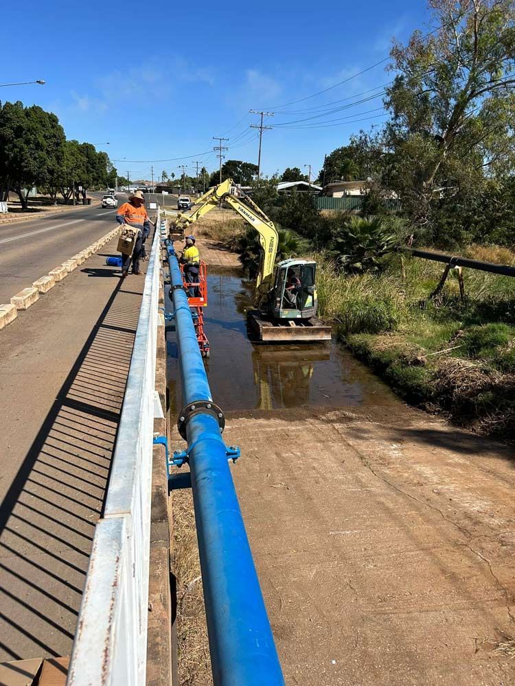 A Group Of People Are Working On A Bridge Repairing The Water Pipe — NQES Industries in Ryan, QLD