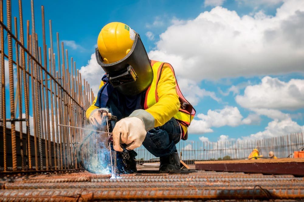 A Construction Worker Is Welding A Metal Structure At A Construction Site — NQES Industries in Ryan, QLD