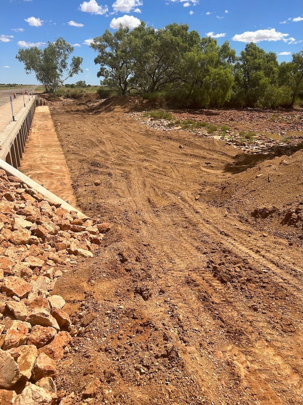 A dirt road in the middle of a field with trees in the background — NQES Industries in Ryan, QLD