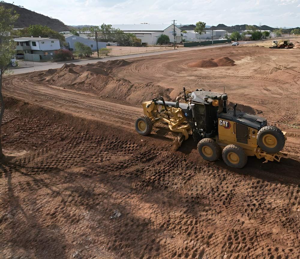 A Cat Excavator Is Driving Through A Dirt Field — NQES Industries in Ryan, QLD 
