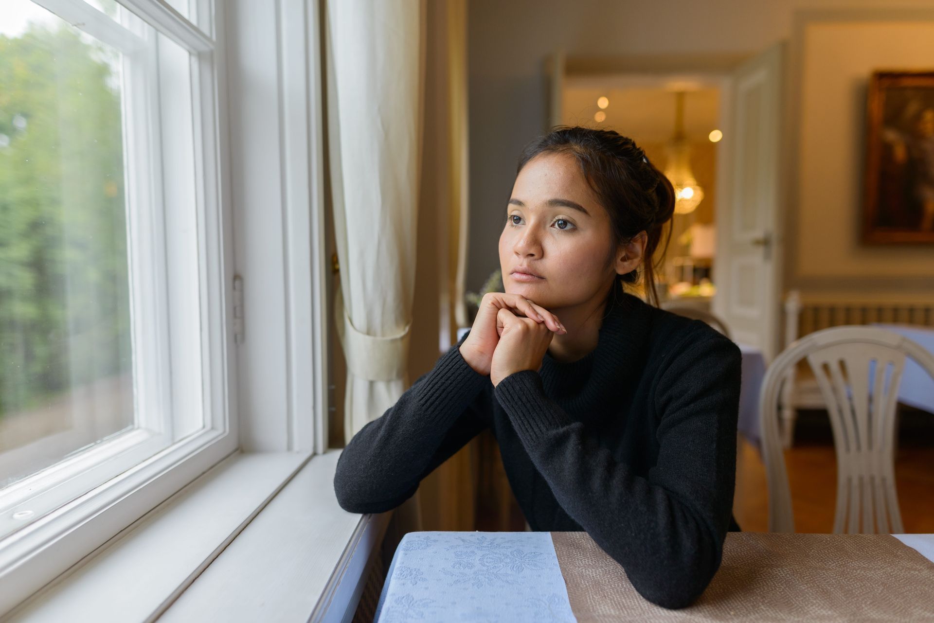 A woman sitting thoughtfully by a window, representing depression counseling in Fairfax VA with Lisa